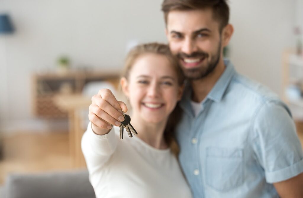 Young couple holding keys to their new home.